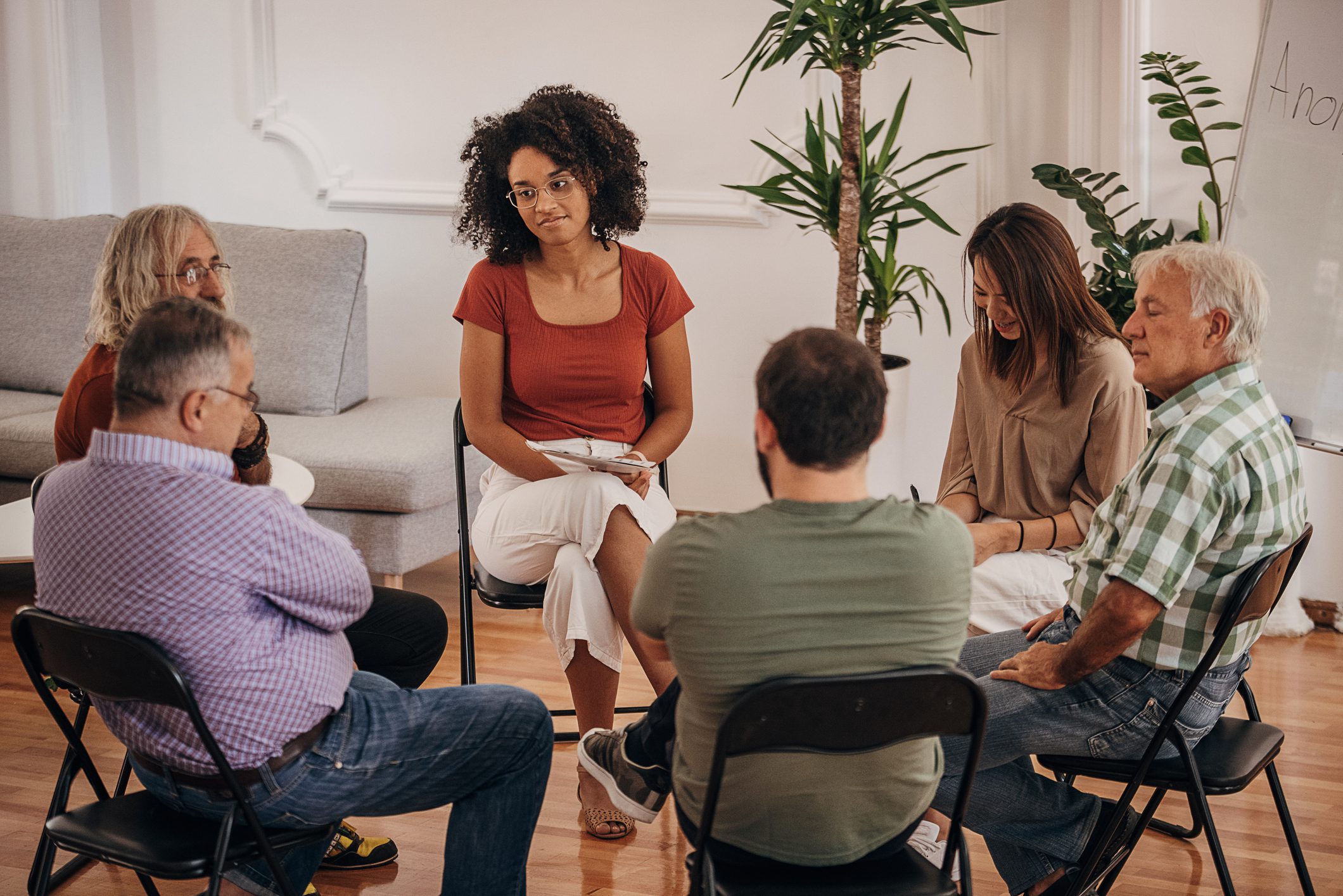 People sitting in support group Adults sitting in a close circle during a group therapy session